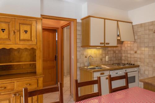 uma cozinha com armários de madeira e um lavatório em Le petit chez soi em Châtel