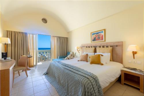 a hotel room with a large bed and a desk at Giannoulis - Santa Marina Plaza (Adults Only) in Agia Marina Nea Kydonias