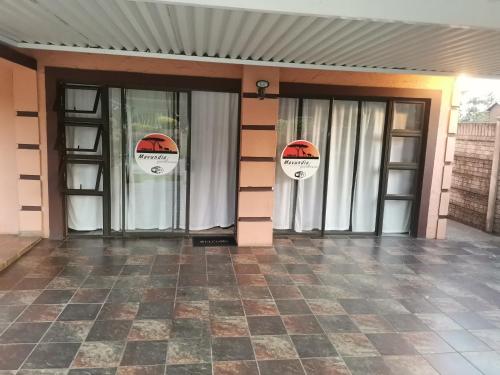 twee glazen deuren van een gebouw met borden erop bij Mavundla guest house in Richards Bay