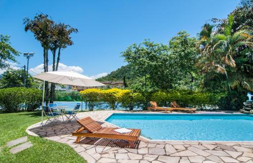 a swimming pool with a chair and an umbrella at Pousada Brazish in Paraty