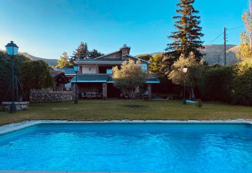 Bustarviejo的住宿－Casa Rural LOS TINES，房子前面有蓝色的游泳池的房子