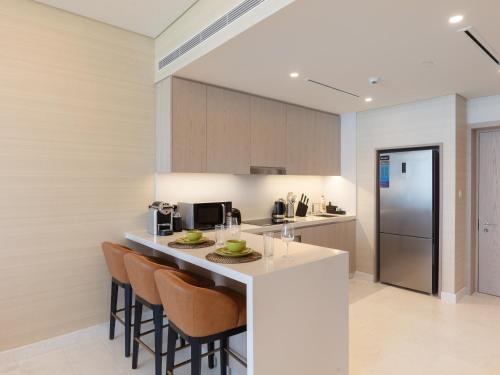 Luxury Living & Views -St Regis High Floor Suite 4 by Exclusive Holiday Homes في دبي: مطبخ مع بار مع كراسي وكاونتر توب