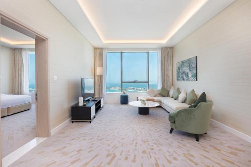 Luxury Living & Views -St Regis High Floor Suite 4 by Exclusive Holiday Homes في دبي: غرفة معيشة بها أريكة وسرير وتلفزيون