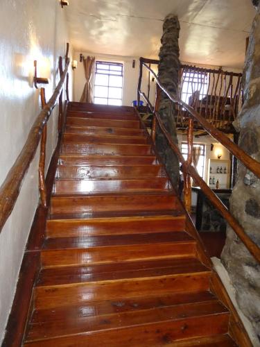 a wooden staircase in a house with a stone wall at Ngari Hill EcoLodge, Maralal - Kenya in Maralal