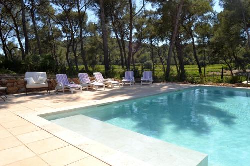 une piscine avec des chaises longues et une piscine dans l'établissement Les Pieds Tanqués - Maison et Chambres d'hôtes dans le Var -Saint Cyr sur Mer, à Saint-Cyr-sur-Mer