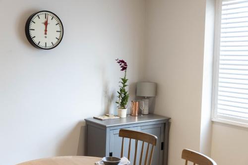 a dining room with a table and a clock on the wall at The Unicorn (Apartments) in Stow on the Wold