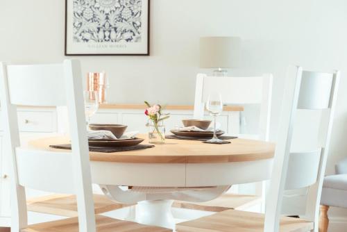 a dining room table with two white chairs and a table with glasses at The Unicorn (Apartments) in Stow on the Wold
