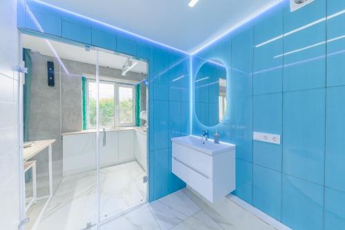 y baño azul con lavabo y ducha. en Квартира-студия c домашним кинотеатром Ocean, en Petropavlovsk