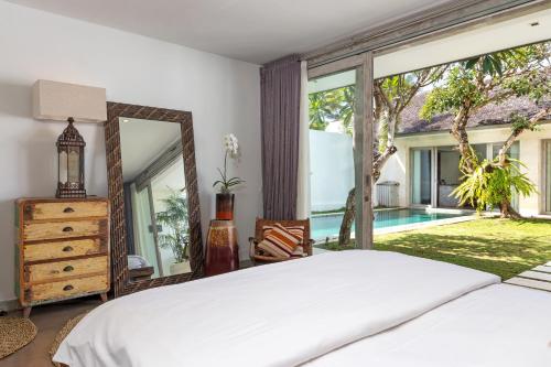 a bedroom with a bed and a mirror and a pool at Villa Mia in Canggu