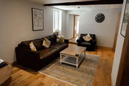 a living room with a leather couch and a coffee table at The Unicorn (Apartments) in Stow on the Wold