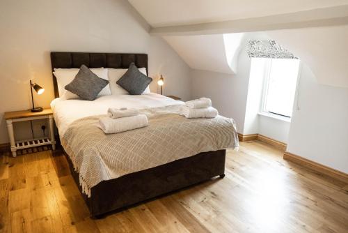 a bedroom with a large bed with towels on it at The Unicorn (Apartments) in Stow on the Wold