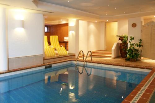 a swimming pool with yellow chairs in a hotel room at Hotel Alpensonne in Riezlern