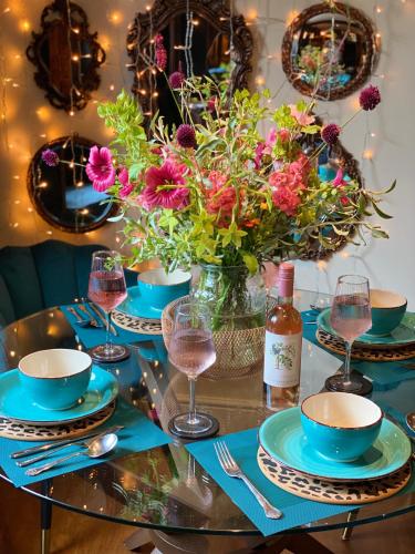 a table with blue plates and flowers and wine glasses at Cramwell Cottage, The Ley Arms in Exeter