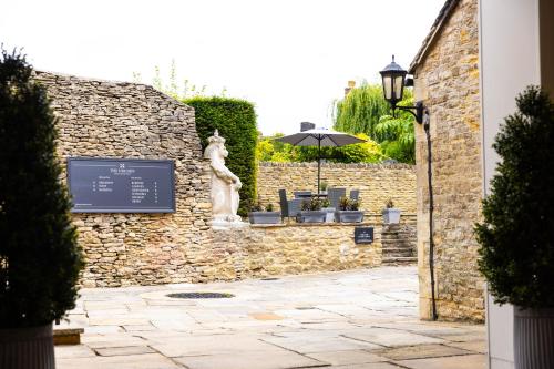 a stone wall with a table and an umbrella at The Unicorn (Apartments) in Stow on the Wold
