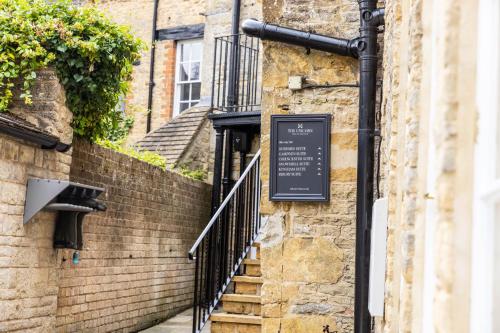 a sign on the side of a brick building with stairs at The Unicorn (Apartments) in Stow on the Wold
