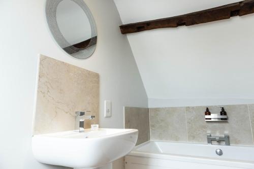 a white bathroom with a sink and a mirror at The Unicorn (Apartments) in Stow on the Wold