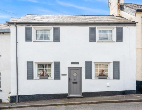 a white house with two windows and a door at Cramwell Cottage, The Ley Arms in Exeter