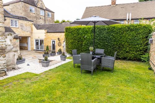 a table and chairs with an umbrella in a yard at The Unicorn (Apartments) in Stow on the Wold