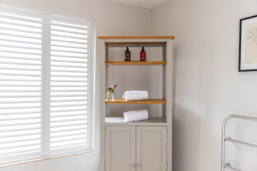 a room with a shelf with towels and a window at The Unicorn (Apartments) in Stow on the Wold