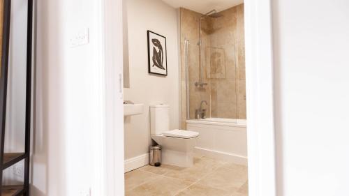 a bathroom with a toilet and a tub and a sink at The Unicorn (Apartments) in Stow on the Wold