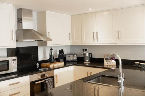 a kitchen with white cabinets and a sink at The Unicorn (Apartments) in Stow on the Wold