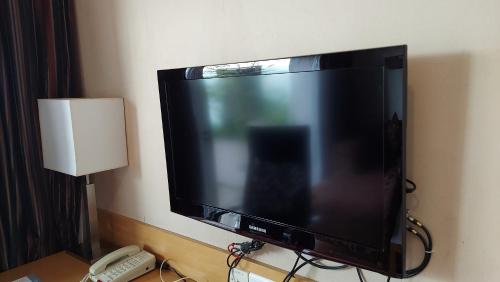 a flat screen tv on a wall with a phone at Mysore County Retreat in Mysore