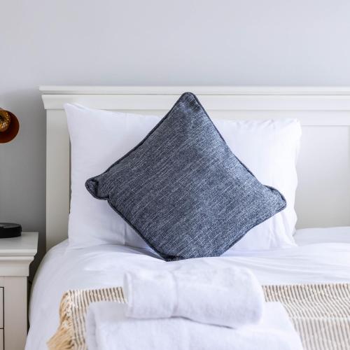 a gray pillow sitting on top of a white bed at The Unicorn (Apartments) in Stow on the Wold