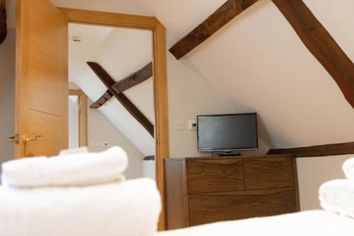 a bedroom with a tv on a dresser with a mirror at The Unicorn (Apartments) in Stow on the Wold