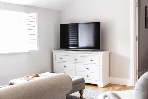 a living room with a tv on a white dresser at The Unicorn (Apartments) in Stow on the Wold