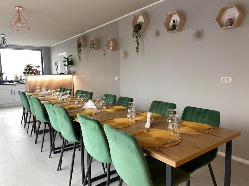 a long wooden table and green chairs in a room at Casa Mina Divici in Divici