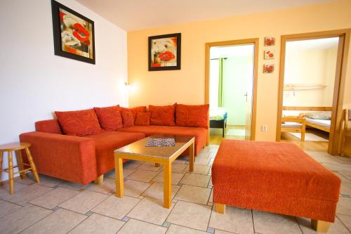 a living room with an orange couch and a table at Ski apartmány Spiežovec Donovaly in Donovaly