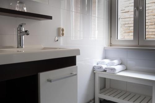 a white bathroom with a sink and towels at Hotel La Casa in Valkenburg