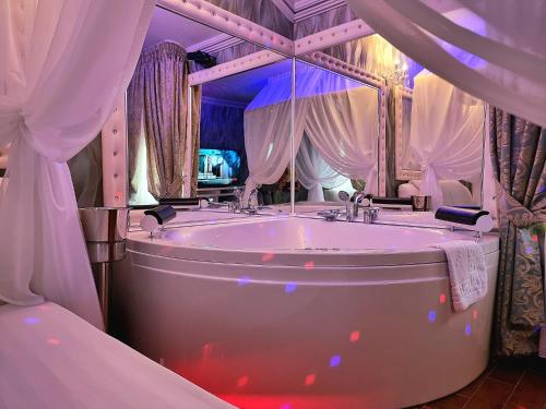 ein großes Bad mit einer Badewanne und einem großen Spiegel in der Unterkunft Anadi Hotel Boutique in Braşov