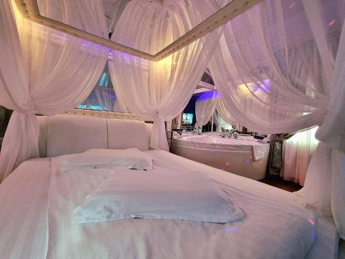 ein Schlafzimmer mit einem weißen Bett mit Vorhängen und einer Badewanne in der Unterkunft Anadi Hotel Boutique in Braşov