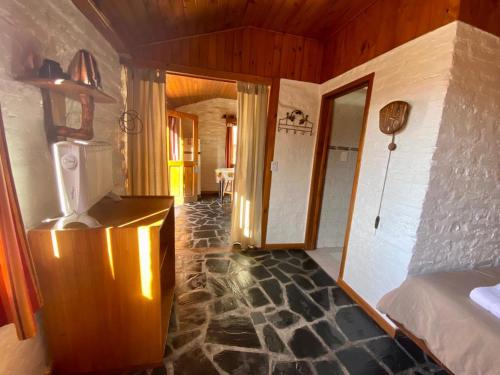 a room with a bed and a room with a stone floor at Hostería & Cabañas Río Fénix in Perito Moreno