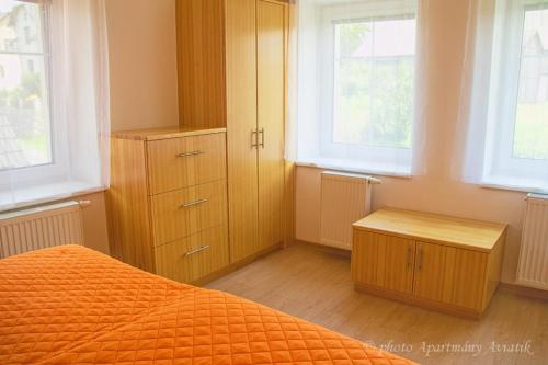 イェセニークにあるAviatik apartmányのベッドルーム(オレンジ色のベッド1台、木製キャビネット付)