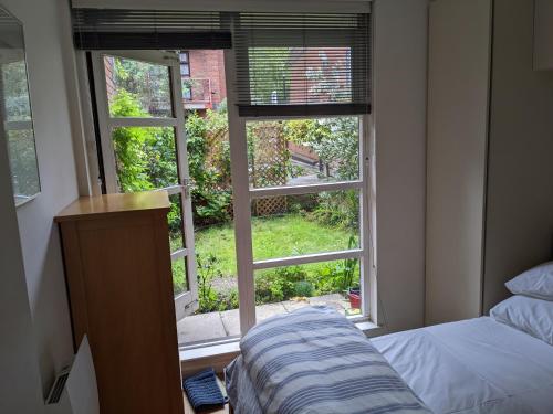 a bedroom with a window looking out at a yard at Rotherhithe apartment near park and river in London