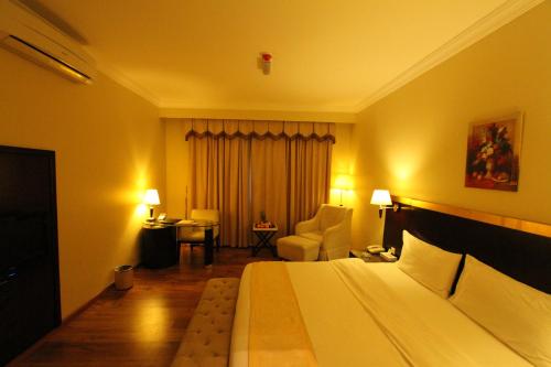 a hotel room with a bed and a chair at Al Maha Residence Rak in Ras al Khaimah
