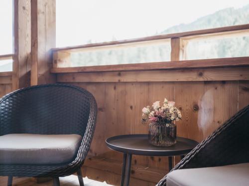 two chairs and a table with a vase of flowers at VAYA Gerlos in Gerlos
