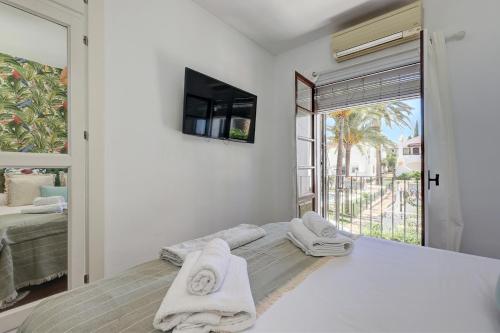 a white bedroom with a bed with towels on it at Casa Alegría - Family home 1 km from Marbella Center in Marbella