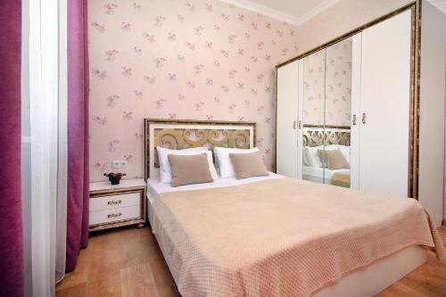- une chambre avec un grand lit et du papier peint rose dans l'établissement 2-комнатная квартира в ЖК Гагарин Парк, à Almaty