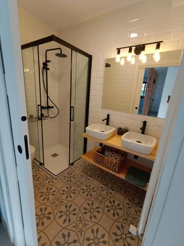 a bathroom with two sinks and a shower and a mirror at Espasante Beach Resort in O Porto de Espasante
