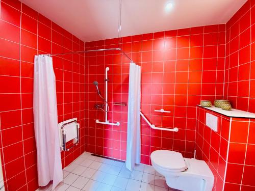 ein rot gefliestes Bad mit einem WC und einer Dusche in der Unterkunft Cap Orne in Amayé-sur-Orne