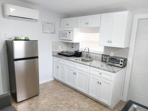 a kitchen with white cabinets and a stainless steel refrigerator at The Torres' Loft West Tampa MidTown Raymond James Stadium in Tampa