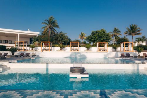 a pool at a resort with chairs and palm trees at Safira Blu Luxury Resort & Villas in Nungwi