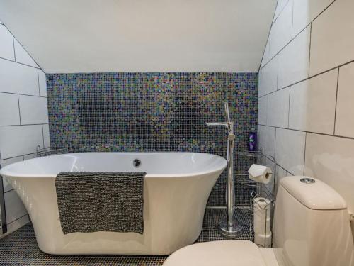 a bathroom with a bath tub and a toilet at Lesta Cottage in Everingham
