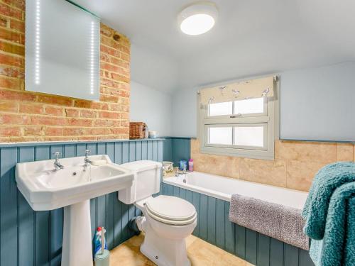 a bathroom with a sink and a toilet and a bath tub at Sunny House By The Sea in Dymchurch