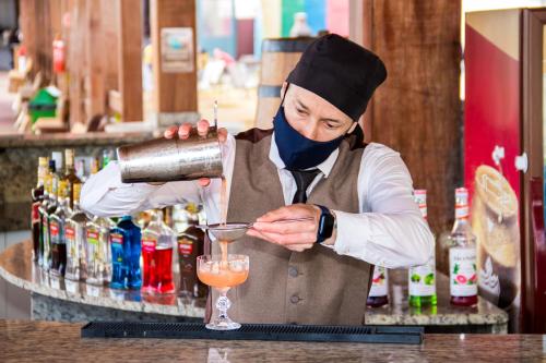 a man is making a drink at a bar at Cassino All Inclusive Resort Poços de Caldas By Nacional Inn in Poços de Caldas