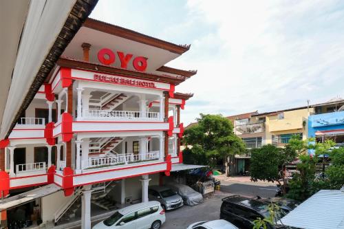 un edificio rosso e bianco con un segno vco sopra di OYO 1384 Pulau Bali Hotel a Denpasar