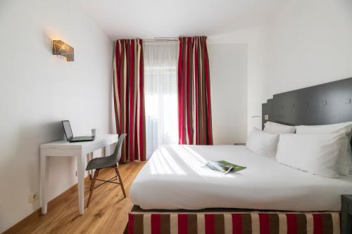 a bedroom with a bed and a desk with a laptop at Hotel Cerise Chatou in Chatou
